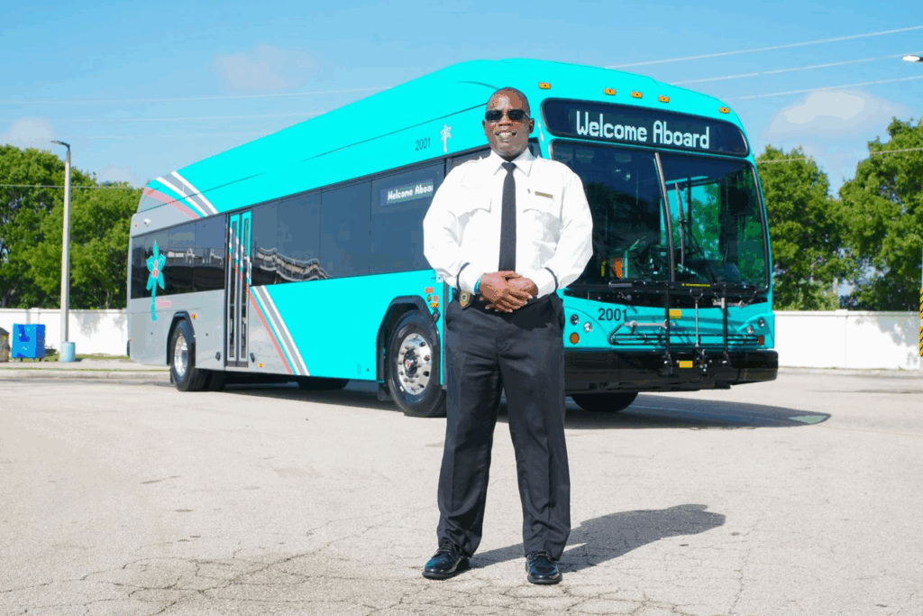 Bus driver standing in front of his bus.