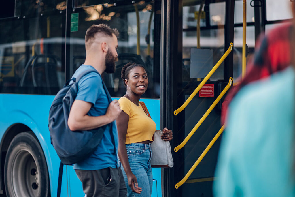 Diverse group of friends waiting for a bus while at a bus stop.