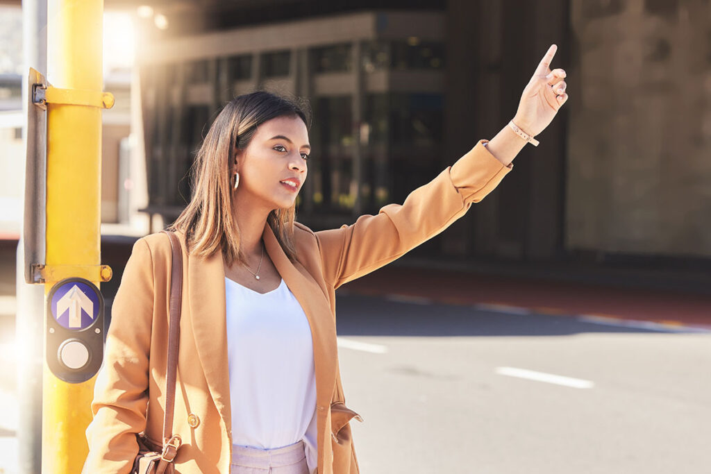 a woman at a bus stop pointing up to catch the bus