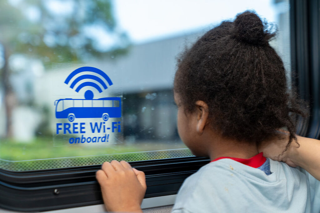 a girl looking at a sign that says "free wi-fi"
